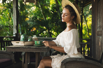 Obraz premium Happy woman sitting on the summer terrace and drinking coffee