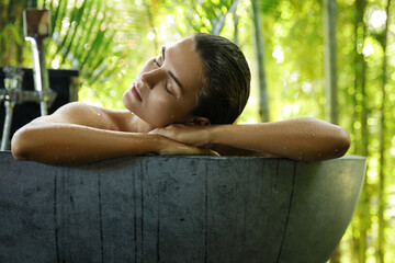 Woman relaxing in bathtub in open air bathroom
