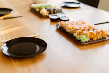 Close up of mix of sushi rolls on a table at home. Waiting friends to eat sushi rolls together using bamboo sticks.