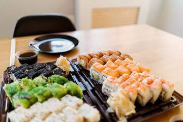 Close up of mix of sushi rolls on a table at home. Waiting friends to eat sushi rolls together using bamboo sticks.