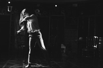 Black and white portrait of beautiful dancing caucasian girl with dramatical emotion on the stage.Retro fashion. Black and white image.