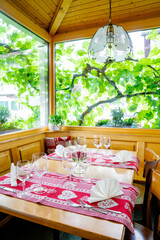 charming and inviting restaurnt table with a bay window and grapevines behind with colorful place settings