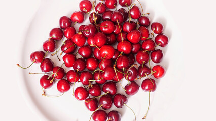 Top view of a lot of fresh sweet cherry fruit berries with water drops. Close-up on the white background. Large collection of fresh red cherries. Ripe cherries texture