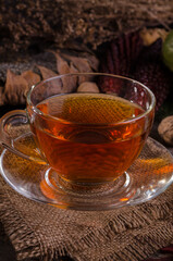 Autumn cozy still life with Glass teapot and cup of tea on a gunny napkin, sunflower, brown maizes and physalises. Good For Social Media Posts.