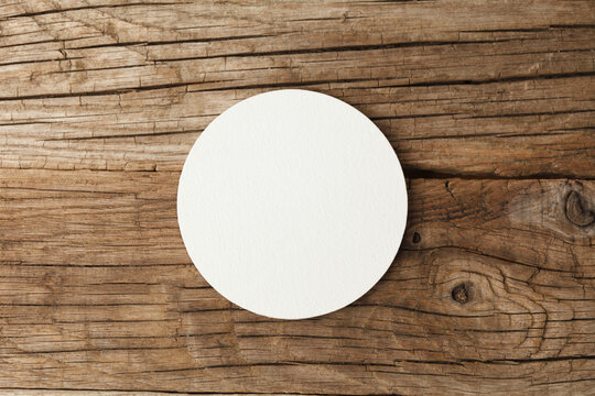 Beer coaster mockup on wooden background.