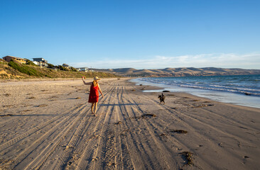 Fototapeta na wymiar Mature woman and pet dog walking together on empty beach in the new normal after coronavirus