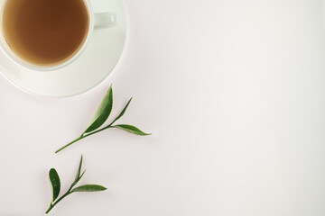 White cup of tea with fresh green tea leaves isolated on white background