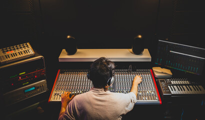 back of asian producer, dj, sound engineer mixing music in recording, broadcasting studio
