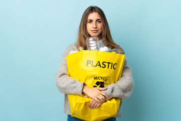holding a bag full of plastic bottles to recycle over isolated blue keeping arms crossed