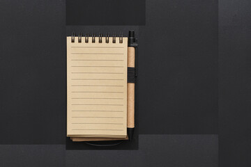 Yellow-black notebook and pen on the table with black and grey patterns. Copy space. 