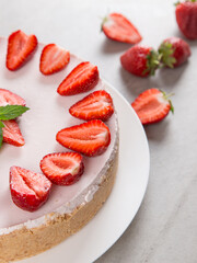 Sweet breakfast, delicious cheesecake with fresh strawberries and mint, homemade recipe without baking, on a stone table. Copy space.