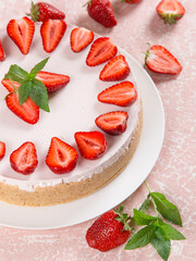 Sweet breakfast, delicious cheesecake with fresh strawberries and mint, homemade recipe without baking, on a pink stone table. Copy space.