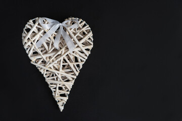 Wicker heart ornament on a black background.
