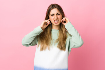 Fototapeta premium Young woman over isolated pink background frustrated and covering ears