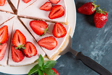 Sweet breakfast, delicious cheesecake with fresh strawberries and mint, homemade recipe without baking, on a dark blue stone table. Copy space.
