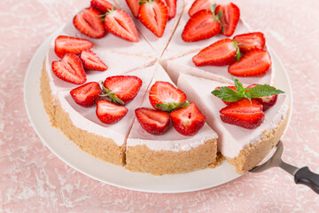 Sweet breakfast, delicious cheesecake with fresh strawberries and mint, homemade recipe without baking, on a pink stone table. Copy space.