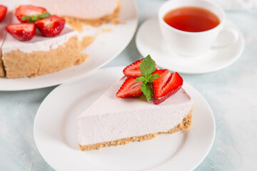 Sweet breakfast, tea and delicious cheesecake with fresh strawberries and mint, homemade recipe without baking, on a blue stone table. Copy space.