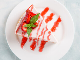 Sweet breakfast, delicious cheesecake with fresh strawberries and mint, homemade recipe without baking, on a blue stone table. Copy space.