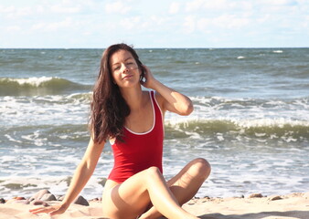 Fototapeta na wymiar A girl in a red swimsuit on the beach of the Baltic sea. Russia. Kaliningrad.