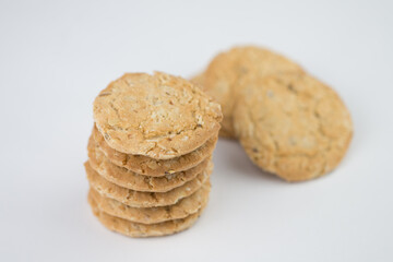 Cereal cookies are stacked on top of several pieces and have three pieces stacked on the back, and the cookies are brown and the image has a blank area next to the object and has a white background