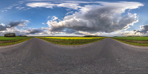 Full spherical seamless panorama 360 degrees angle view on old no traffic asphalt road among fields with cloudy sky in equirectangular projection, VR AR content