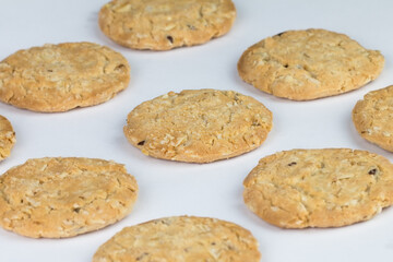 Closeup cereal cookies are arranged in multiple pieces and have three rows, and the cookies are brown and the image has a blank area next to the object and has a white background.