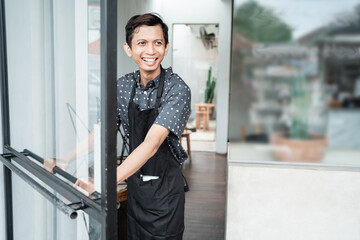 cafe male waitress open the door glass in preparation for opening a shop