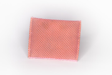 Old sponge for washing dishes, pink sponge Looks through use and has a net covering the sponge and the white background.