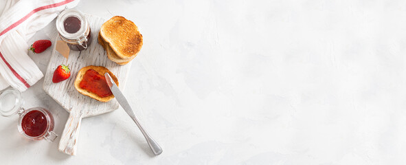Fresh strawberry jam or confiture with crunchy toast for breakfast banner. Top view. Copy space for text. Natural organic food. Seasonal summer food. Banner for bakery or cafe