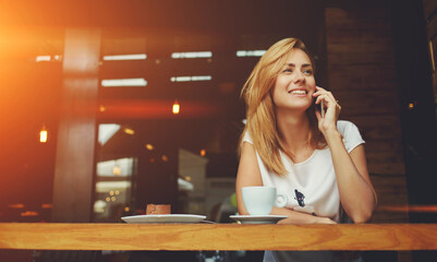  happy hipster girl making photo with cell telephone for a chat with friends while sitting in cafe