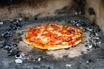 Making of homemade Italian pizza in fireplace brick oven.