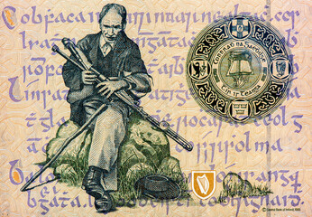 a piper seated on a rock to left with script in the background. Portrait from Ireland 50 Pounds...