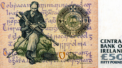 a piper seated on a rock to left with script in the background. Portrait from Ireland 50 Pounds...