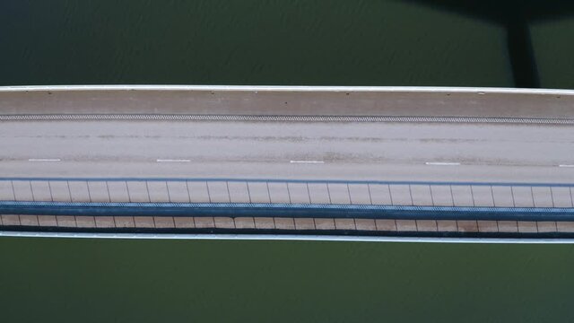 Aerial top down view of highway bridge over river; two lanes, one direction, very low car traffic