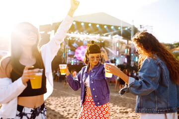 Three female friends drinking beer, dancing  and having fun at music festival. Summer Beach party,...