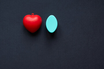 Red heart and blue oval ellipsoid isolated on black background; copy space, top view