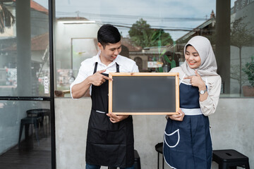 two waitress standing hold a blackboard in front coffee shop when opening