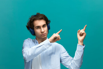 You should read this. Portrait of a young beautiful man wearing white t-shirt and blue shirt in headphones. Point to something top at right by his forefingers