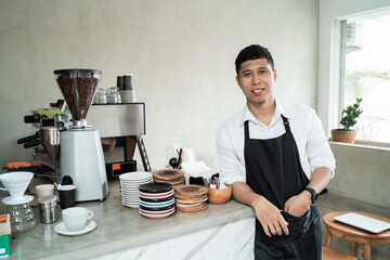 barista with lean back arm standing at workplace in coffee shop