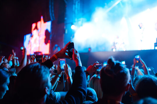 Hand with a smartphone records live music festival, Taking photo of concert stage. Youth, party, vacation concept.