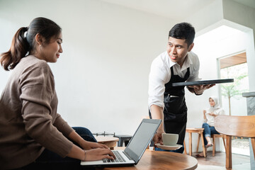 cafe waiter brings orders for a cup of coffee to customer