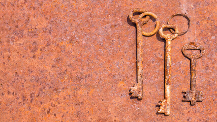3 old rusty keys on ring shot on steel textured background. Copy space.