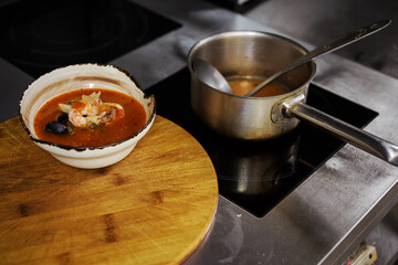 The process of cooking delicious seafood soup with hot and spicy broth, shrimp, mussles, squid. Sauce pan on the induction cooker.