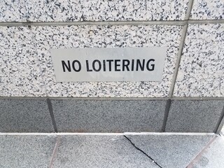 no loitering sign on black and white granite or marble wall