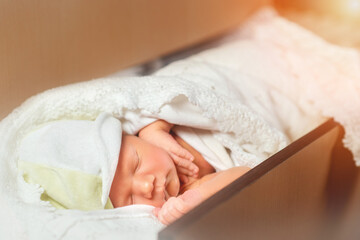 Obraz na płótnie Canvas Close up of cute newborn baby taking nap on white lace sheets. Sweet child resting in shelf in the dresser. Concept of sleeping infant.