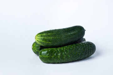 Three green cucumbers on a white background. Harvest from the garden. Ingredient for making salad.
