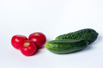 Green cucumbers and tomatoes on a white background. Harvest from the garden. Ingredients for making salad. 