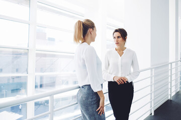 Two female employees having pleasant conversation after analyzing strategy on digital tablet