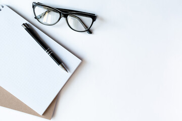 Fototapeta premium Workplace with notebook and glasses on light white backround. Copy space. Close up. Top view. Concept business.