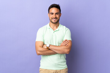 Fototapeta premium Young handsome man isolated on purple background keeping the arms crossed in frontal position